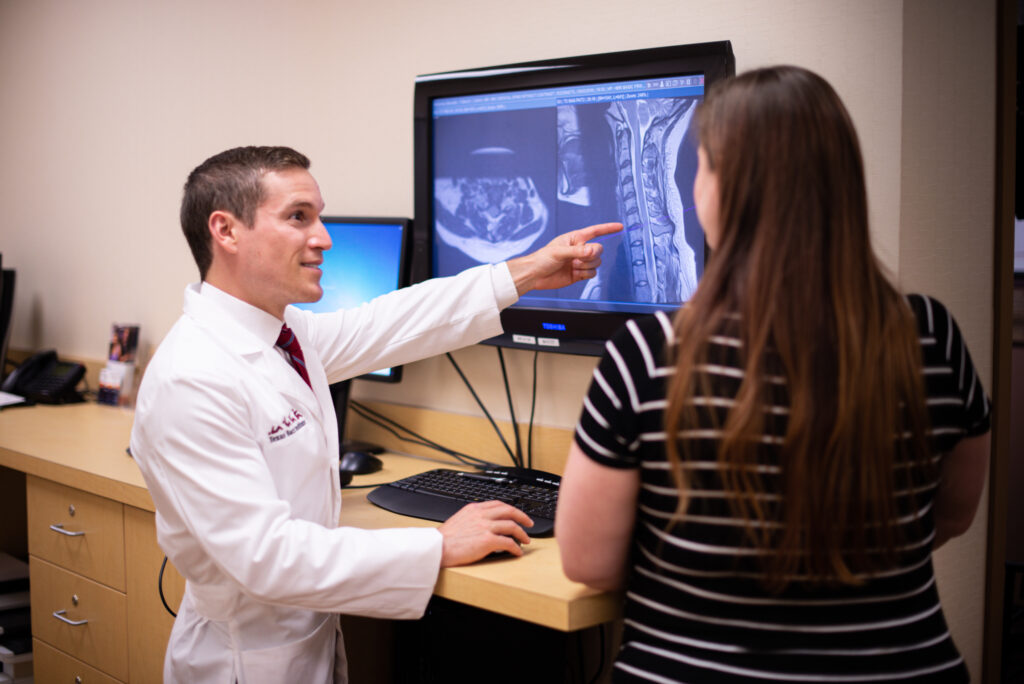 Dr. Derman showing spine image on tv monitor