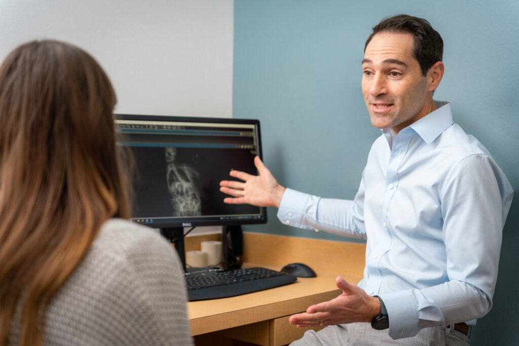 Texas Back Institute Dr. Blake Staub Talking to Scoliosis Patient in Clinic
